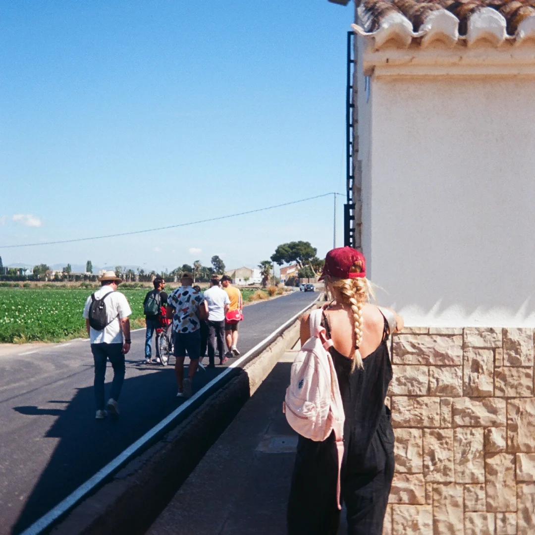 Traveller walking along a rural road with a small group, reflecting immersive, on-the-ground research for tourism and hospitality branding.