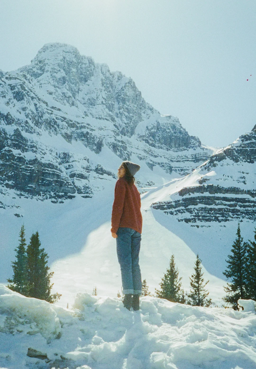 Woman standing in a snowy mountain landscape, reflecting immersive travel research and inspiration for place-based brand strategy.