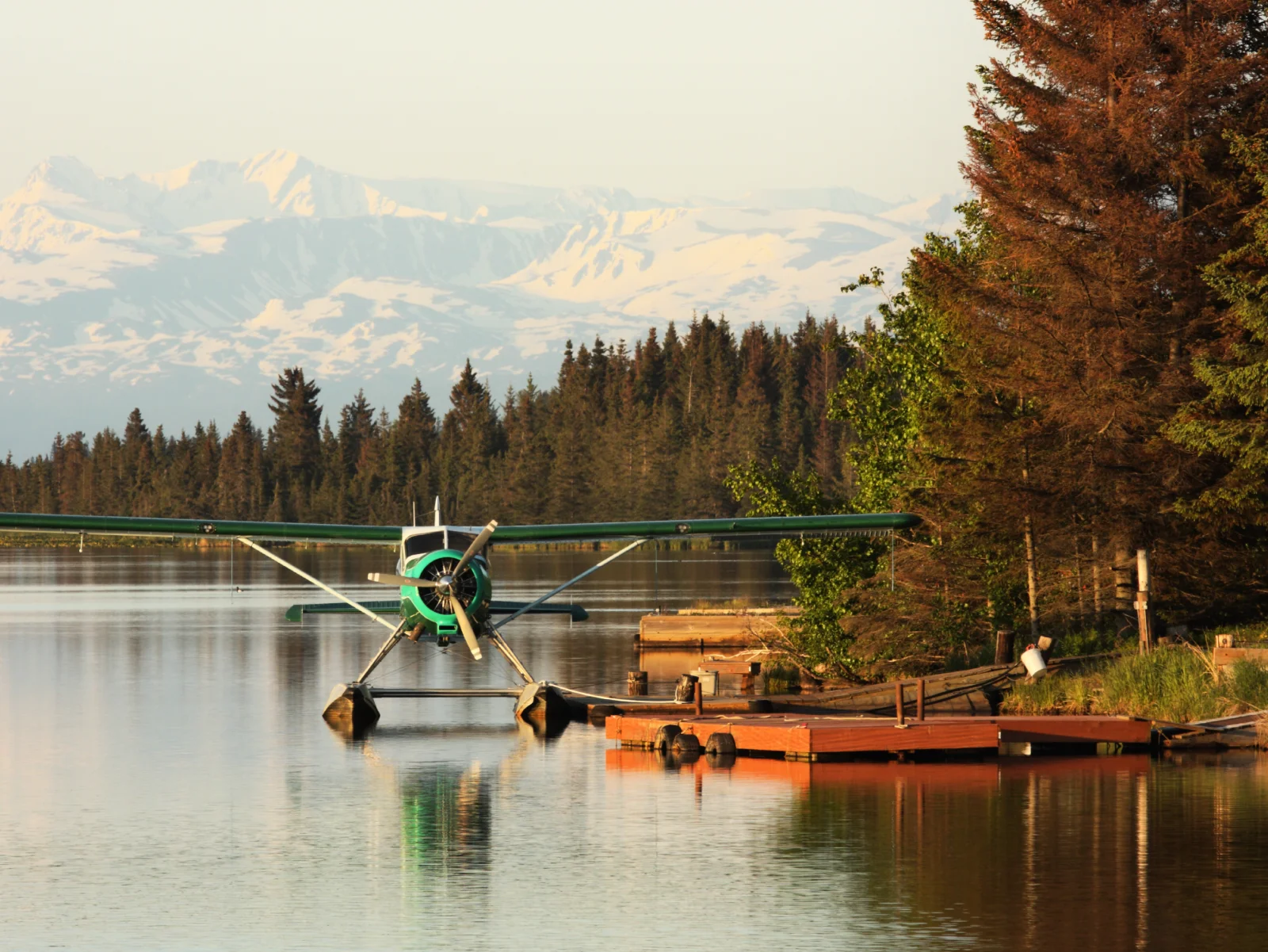 Floatplane parked on a calm lake beside a dock, representing unforgettable hospitality experiences in a wilderness destination.