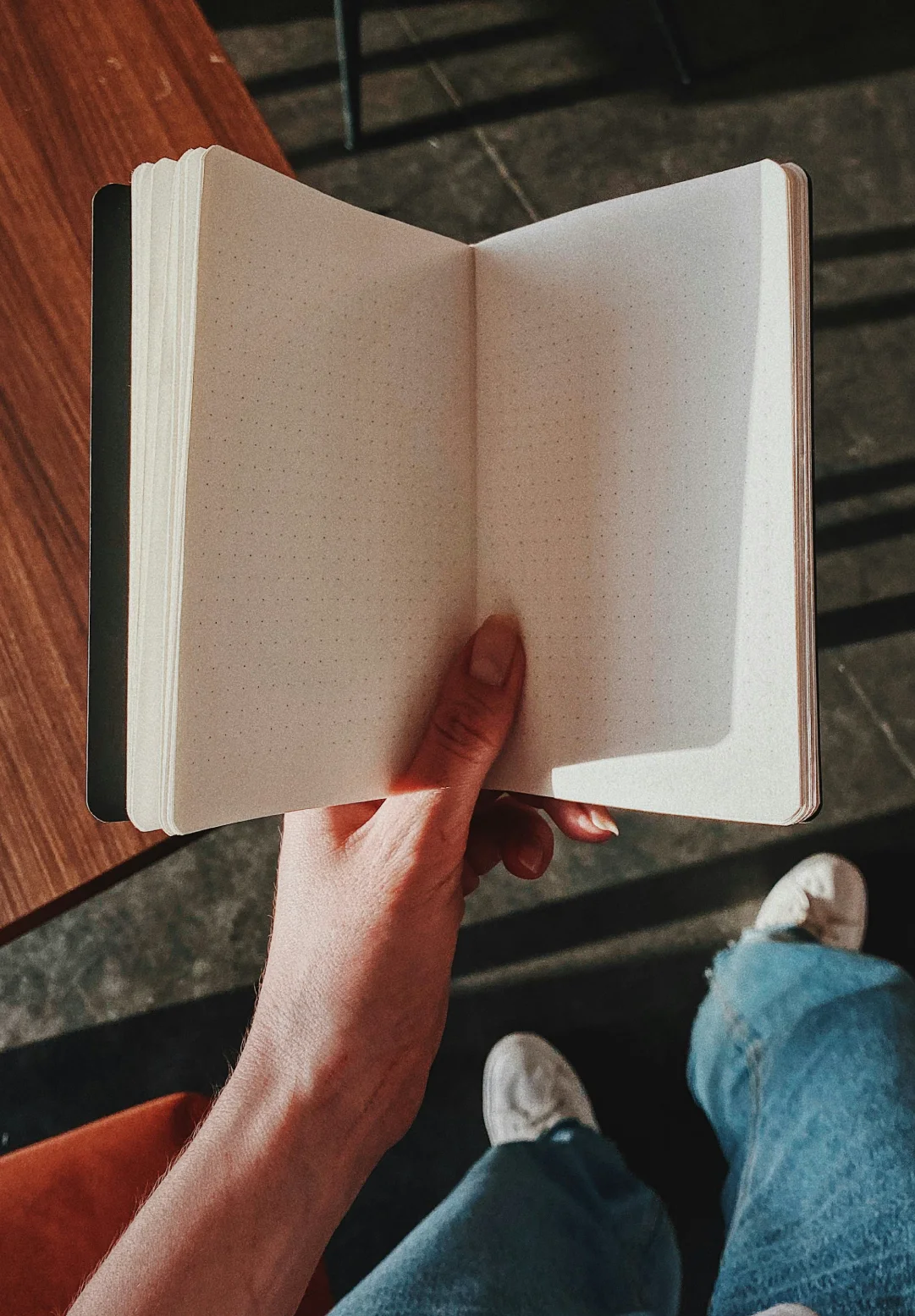 Hand holding an open blank notebook in warm light, representing the early writing process behind brand naming and verbal identity.