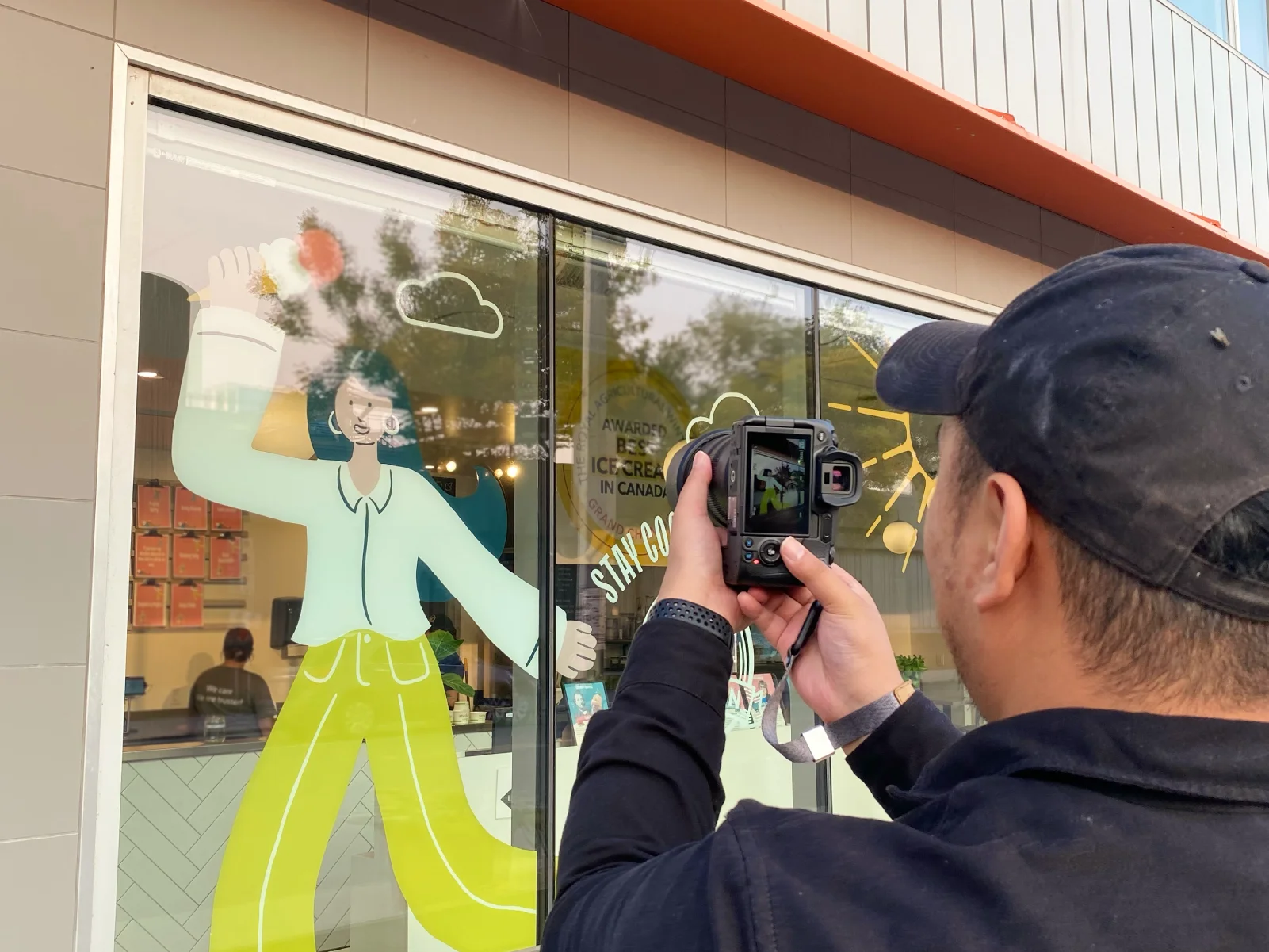Photographer capturing branded storefront window graphics, showing real-world brand rollout and environmental design in action.