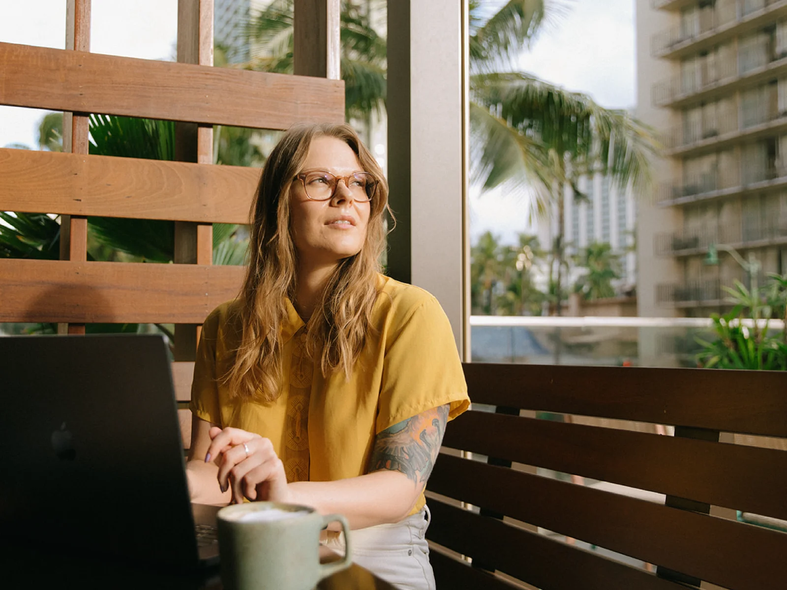 Founder seated outdoors with a laptop and coffee, representing thoughtful brand strategy and creative direction for place-based businesses.