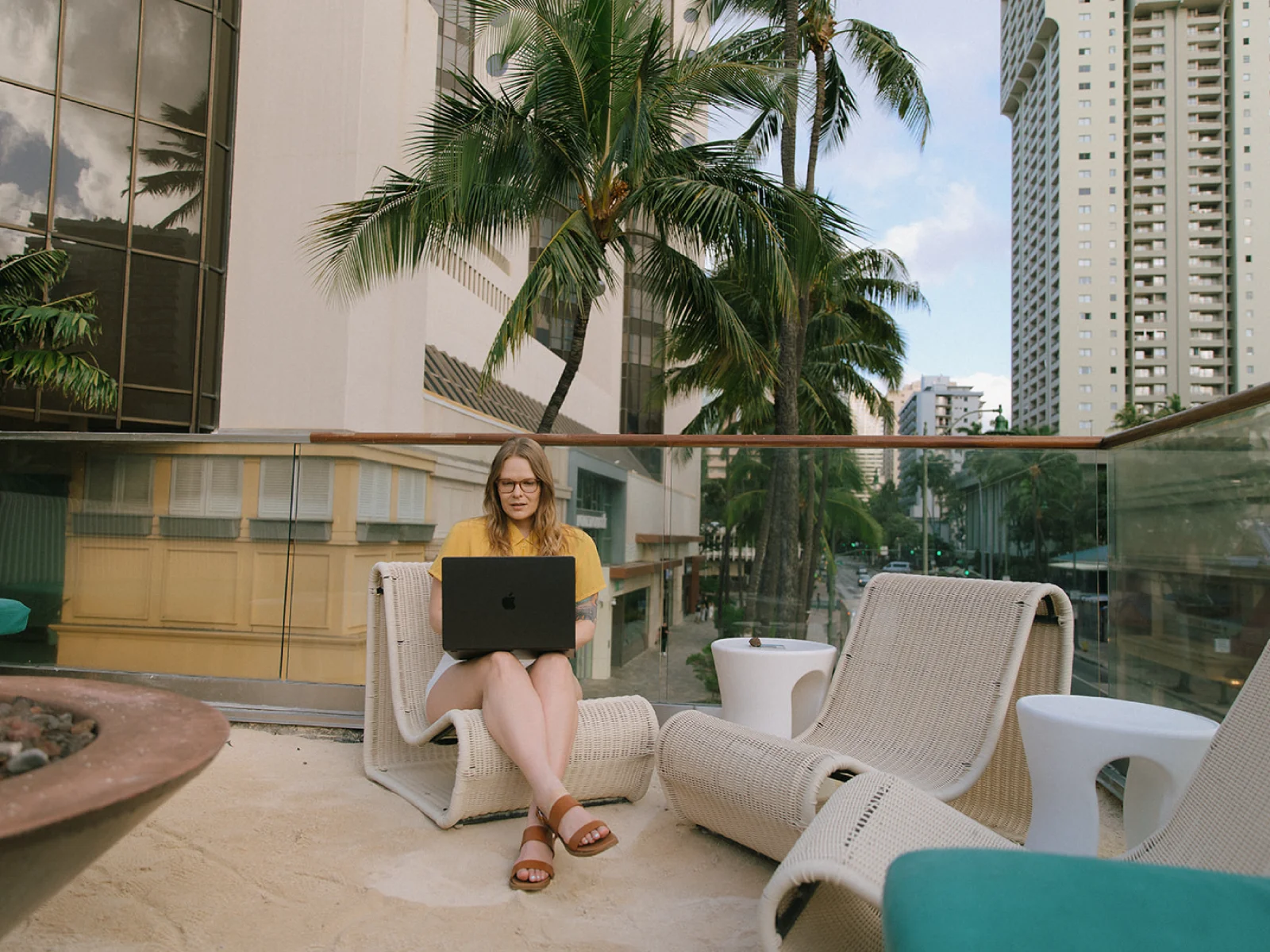 Creative director working on a laptop from a city hotel terrace, reflecting remote strategy work for hospitality and travel brands.