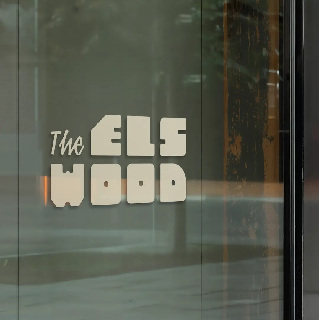 The Elswood logo applied to glass door signage, demonstrating brand expression for an Indigenous-led residential development in Winnipeg.