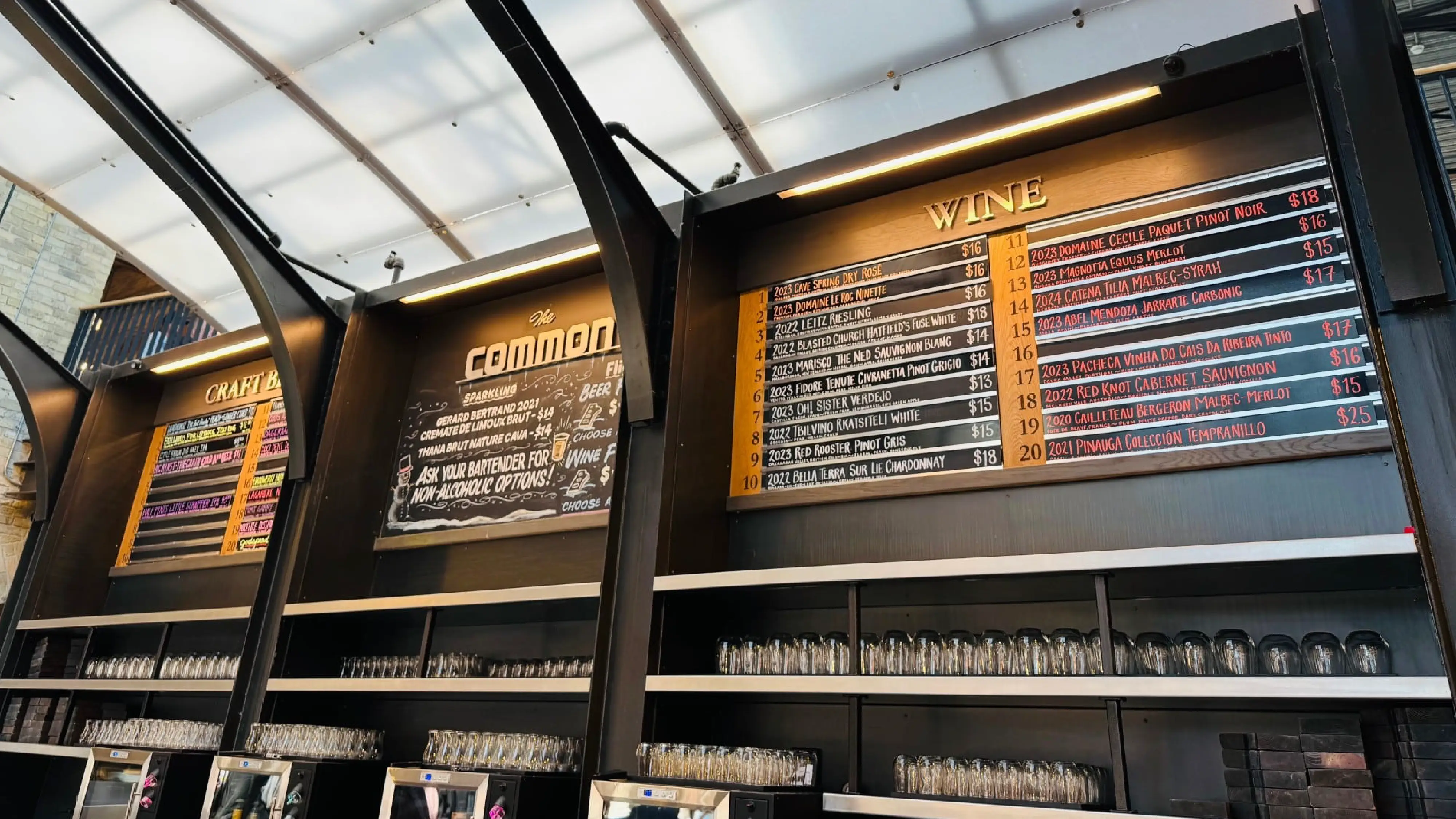 The Common bar inside The Forks Market featuring chalkboard menus of local craft beer and wine, a central hub for Winnipeg visitors.