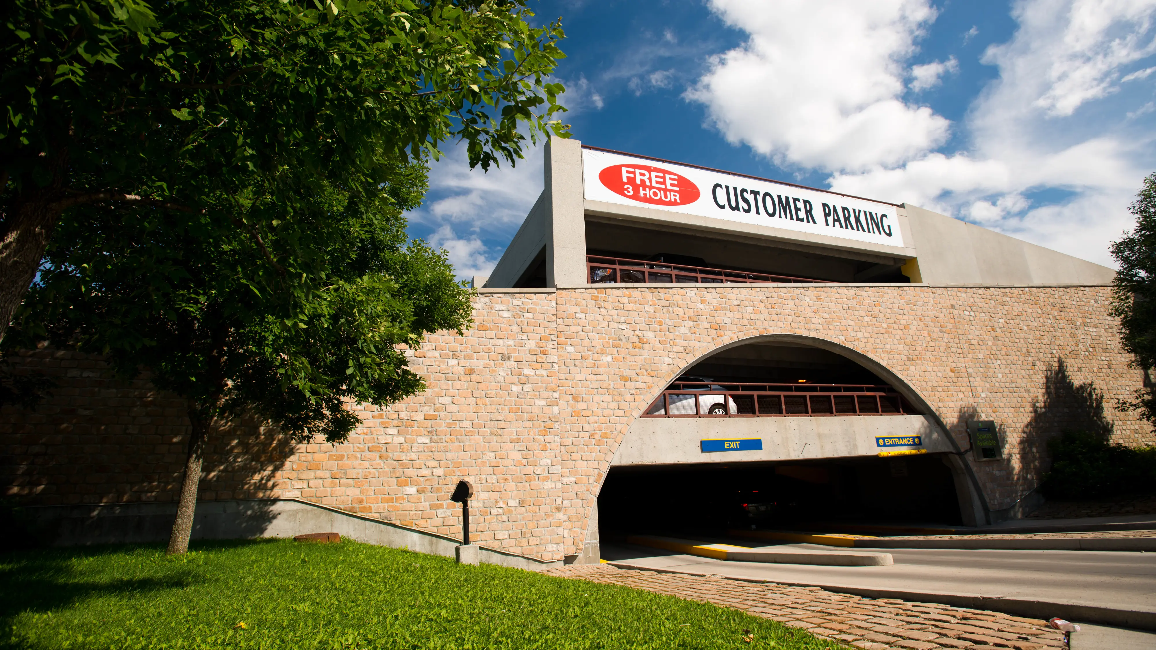 The Forks customer parking structure in Winnipeg with a stone façade and free three-hour parking sign, supporting visitor accessibility.