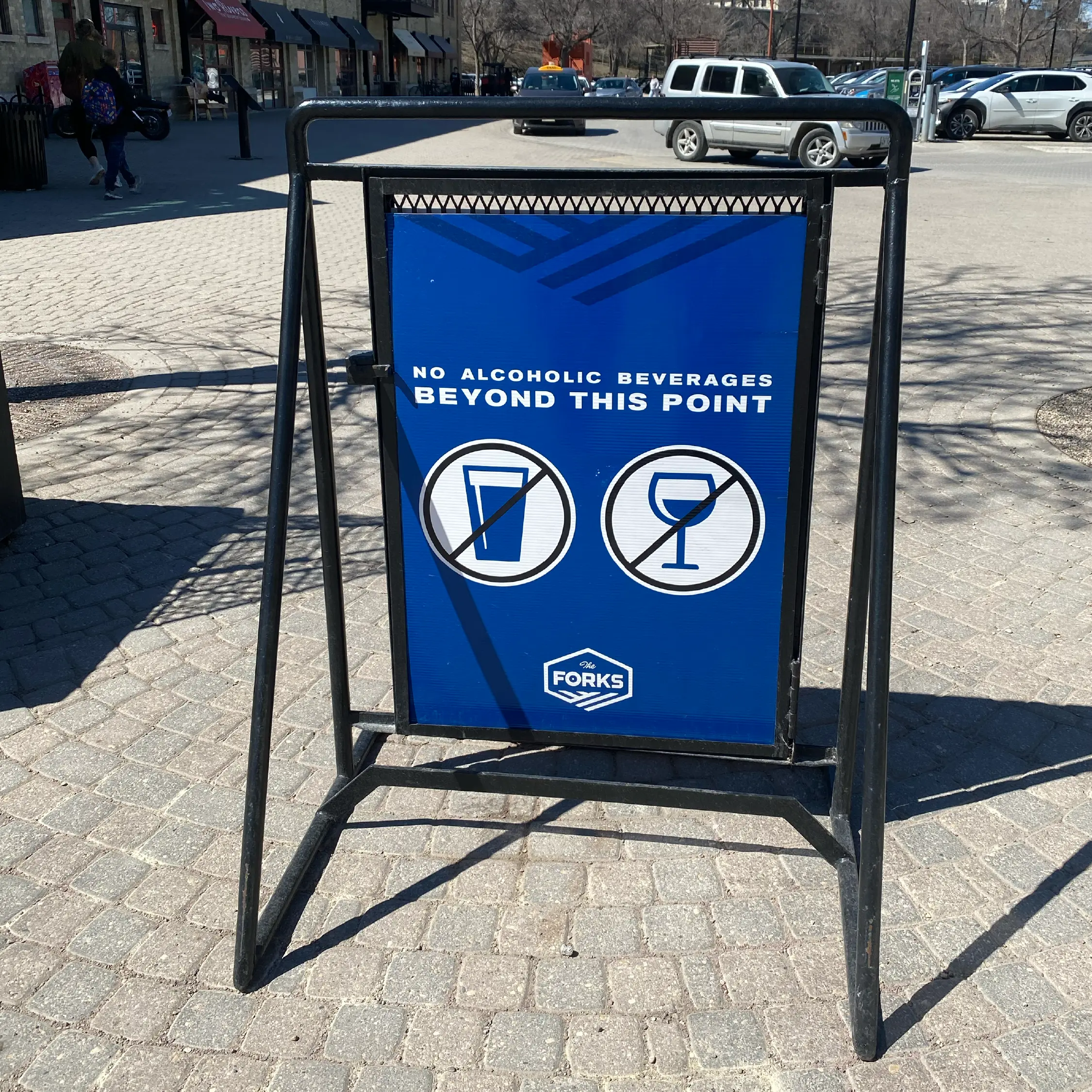 Blue outdoor sign at The Forks Market indicating no alcoholic beverages beyond this point, part of the site’s event zoning and wayfinding system.