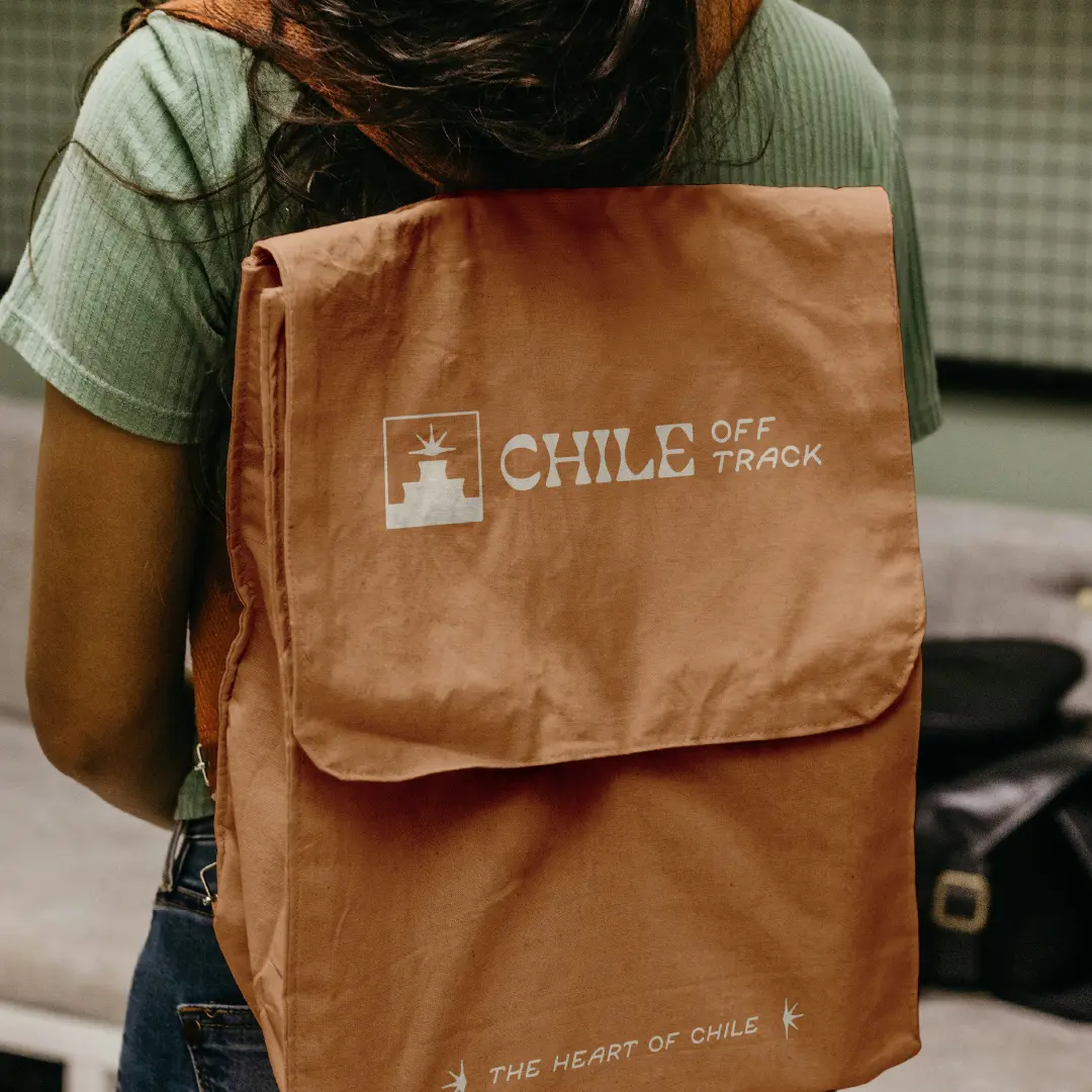 Rust-coloured messenger bag printed with the Chile Off Track logo, worn over the shoulder.