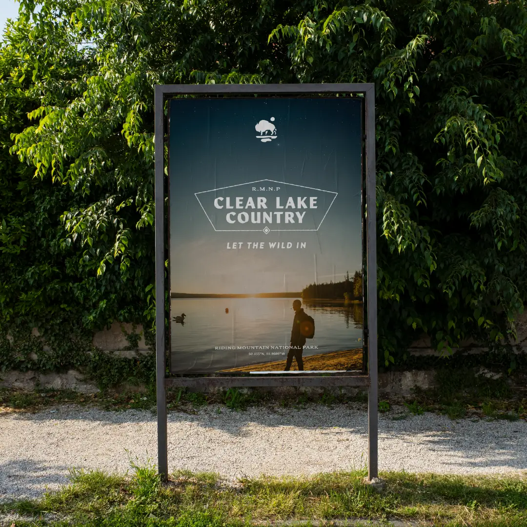 Outdoor sign featuring the Clear Lake Country logo and “Let the Wild In” tagline over a sunset lakeshore scene.