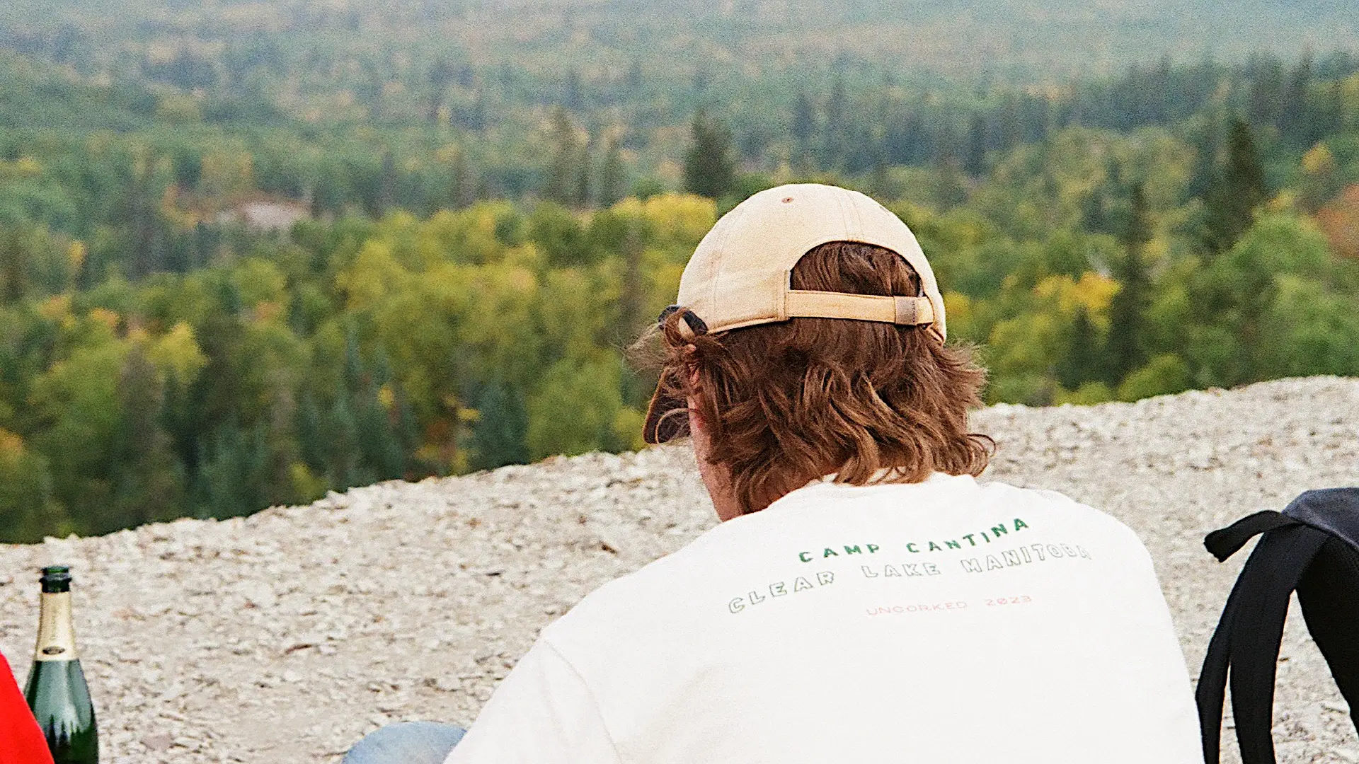 Person wearing a Camp Cantina sweatshirt overlooking forested scenery in Clear Lake, Manitoba.