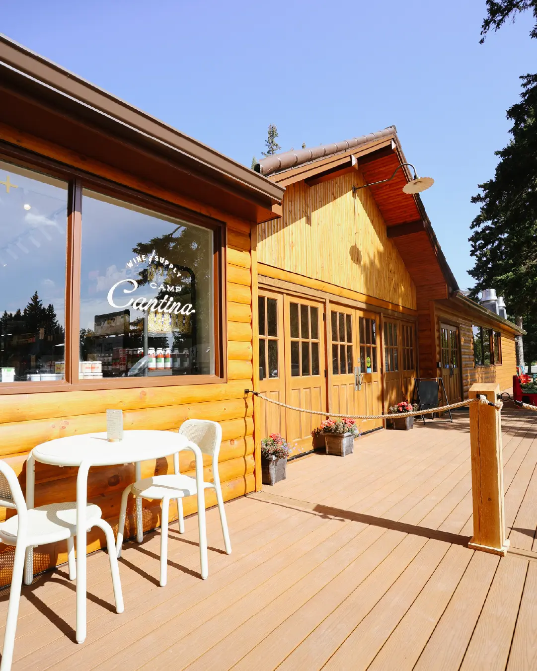 Camp Cantina log-cabin storefront with patio seating and Camp Cantina window decal in Clear Lake, Manitoba.