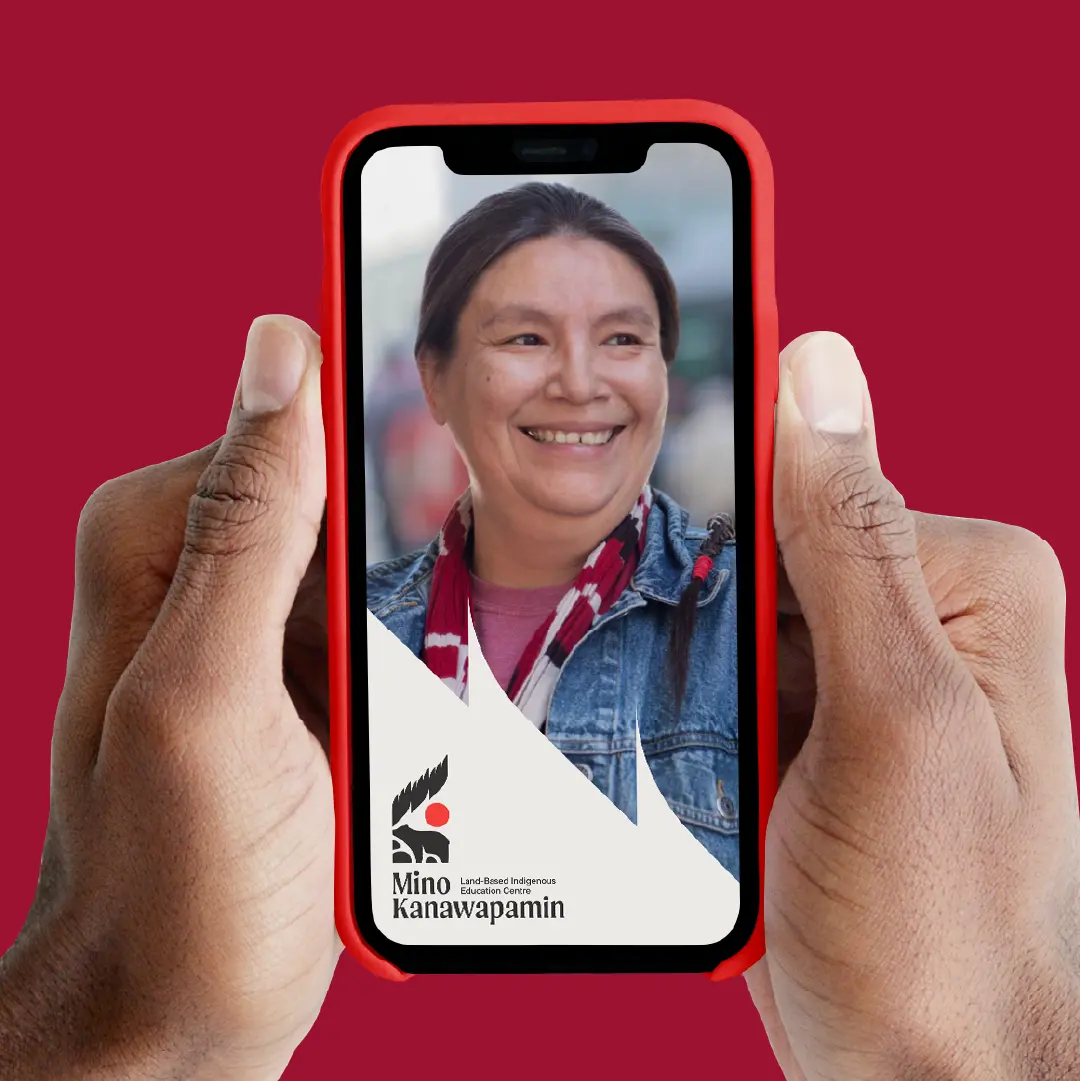 Hands holding a phone displaying a Mino Kanawapamin story-style graphic with a photo and logo overlay.