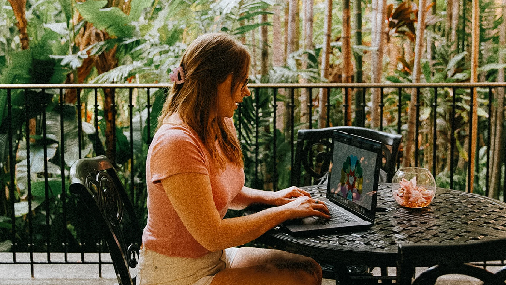 Brand director working on a laptop in a lush courtyard at the Royal Hawaiian hotel.