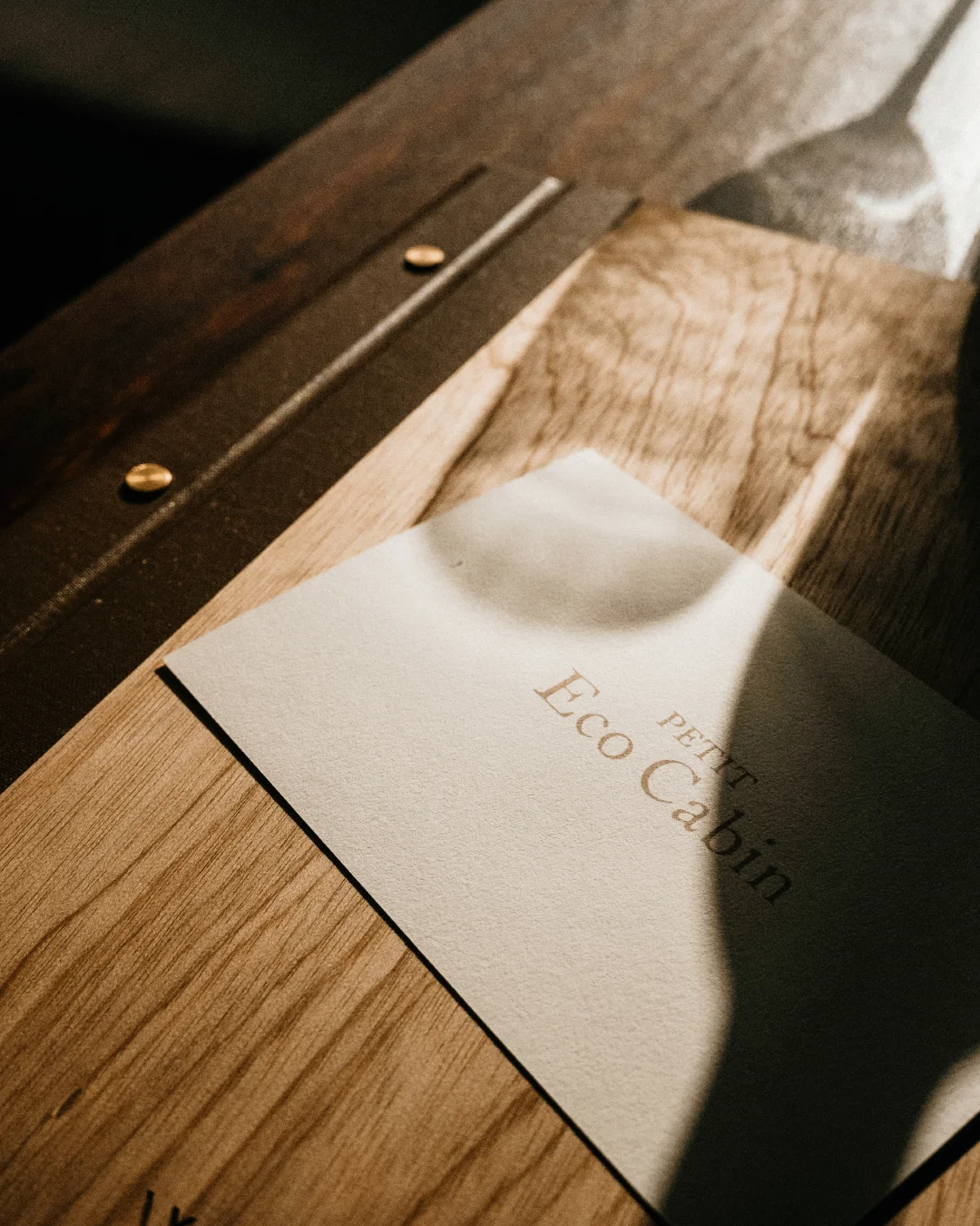 Minimal printed Eco Cabin card placed on a wooden table in warm natural light.