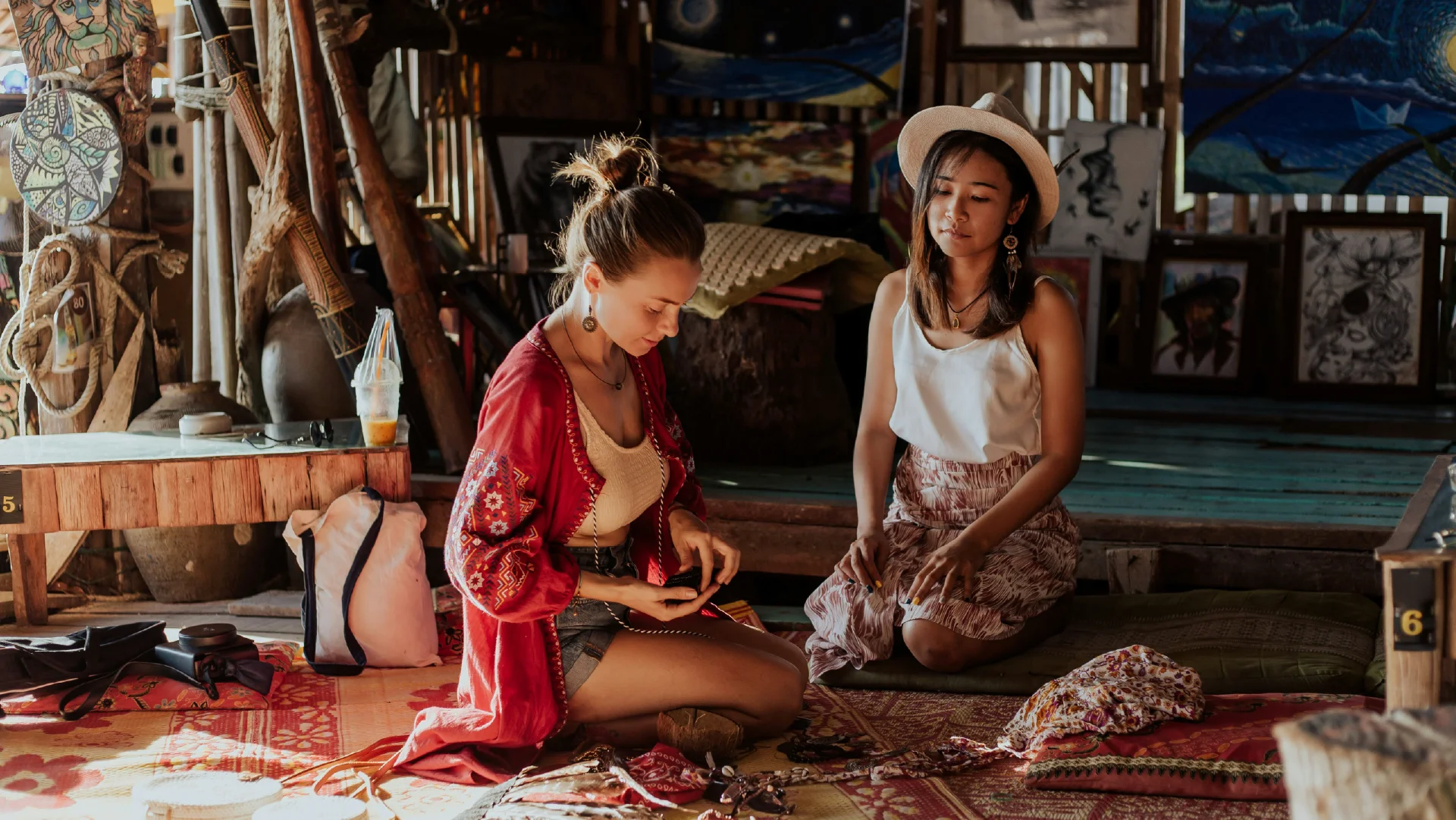 Two travellers sit in a local artisan space surrounded by art, textiles, and handmade objects.