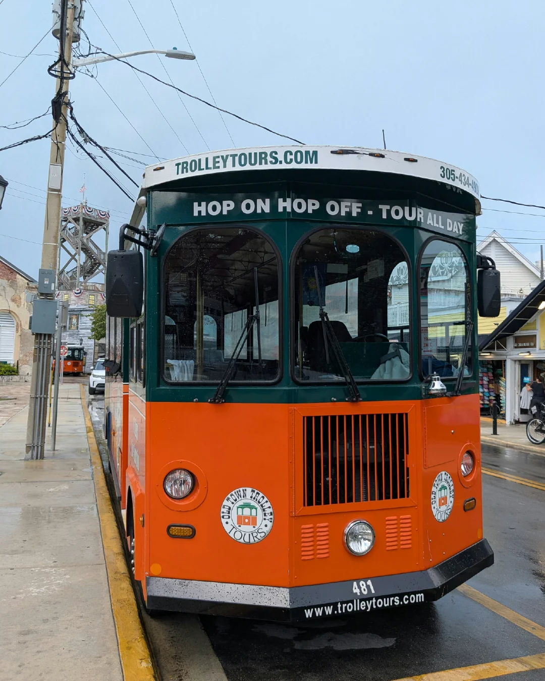 A hop-on hop-off tour trolley on a city street, showing a visible tourism brand touchpoint.