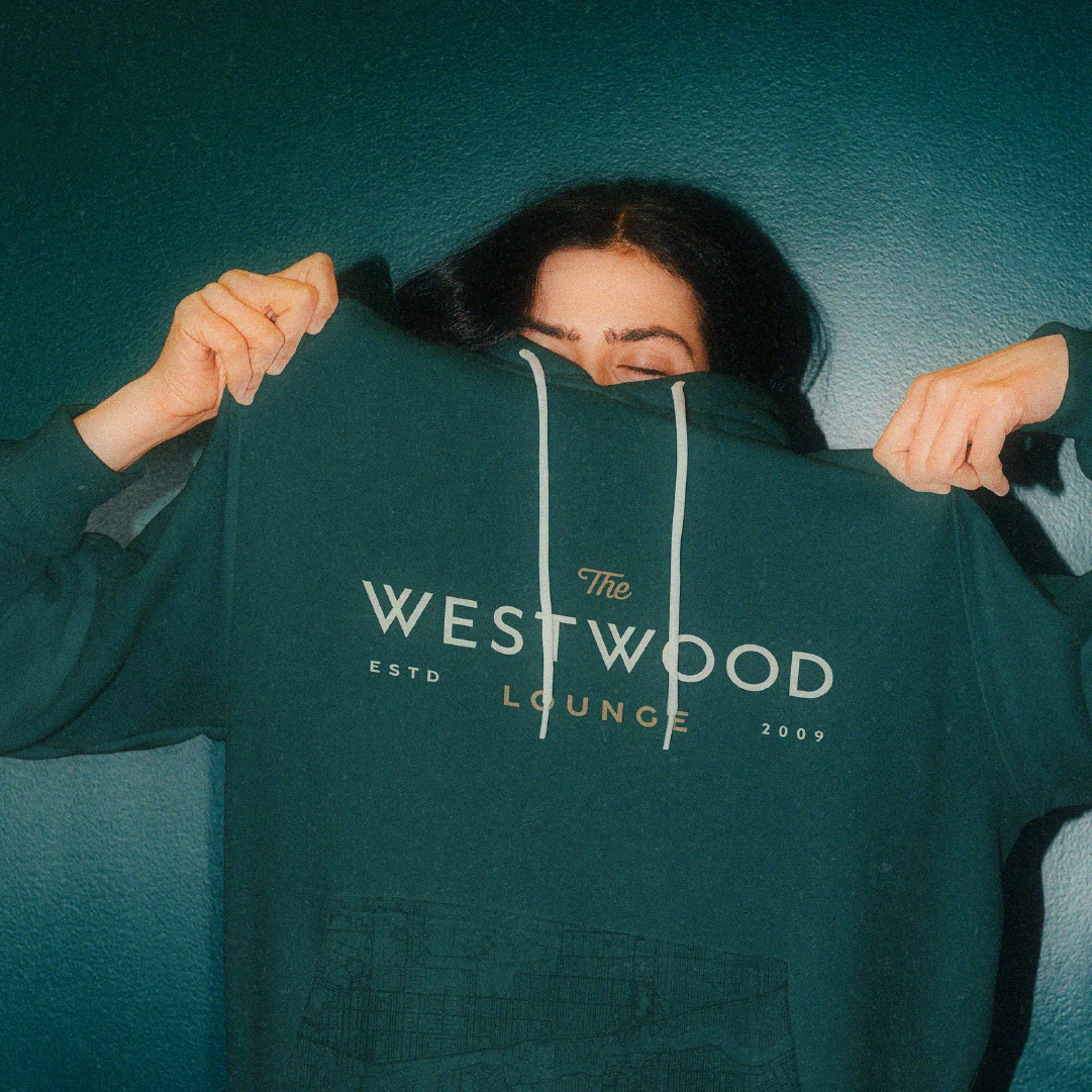 Westwood Lounge hoodie design featuring the restaurant’s logo system in cream and gold on deep green fabric.