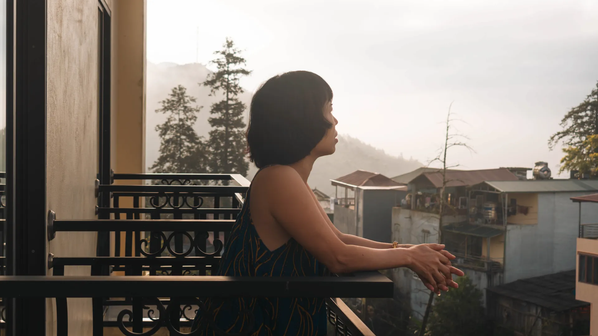 Guest standing on a hotel balcony looking out over a misty mountain village.