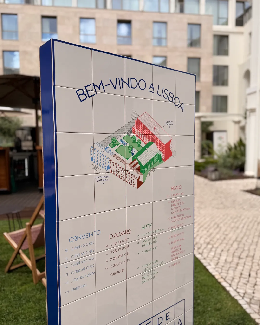 Tiled hotel wayfinding sign with a colourful illustrated map and room directions in a courtyard.
