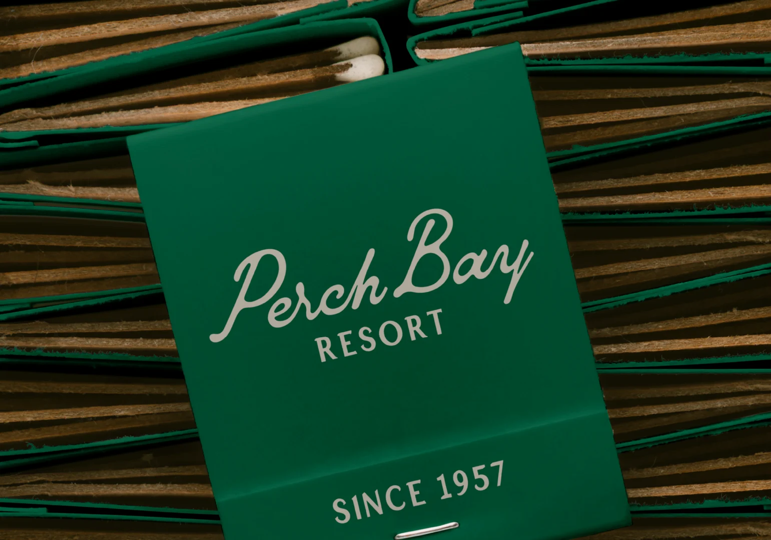 Close-up of a green Perch Bay Resort matchbook featuring the script logo and Since 1957 branding.