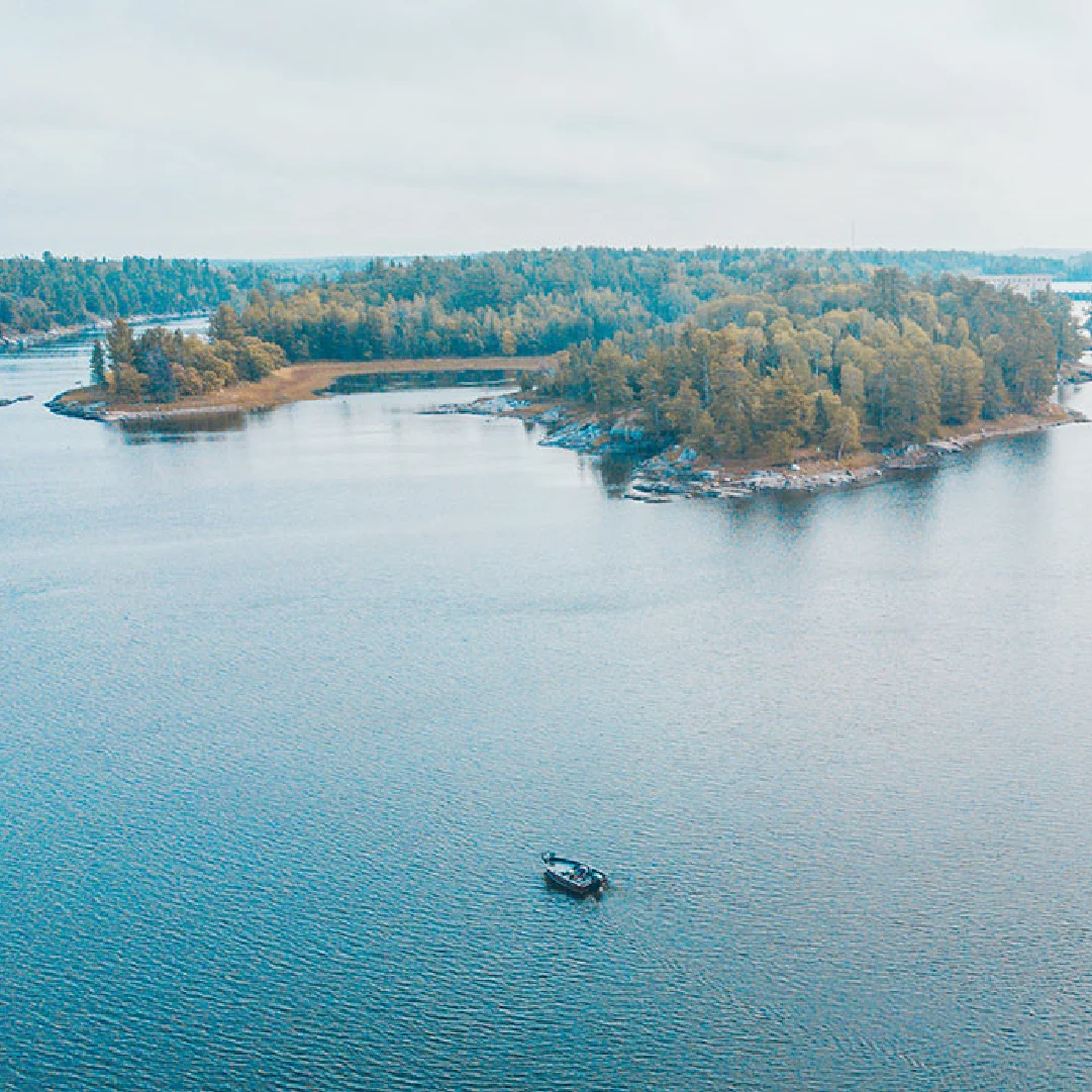 A small boat on the calm water near forested islands in Northern Ontario at Perch Bay Resort.