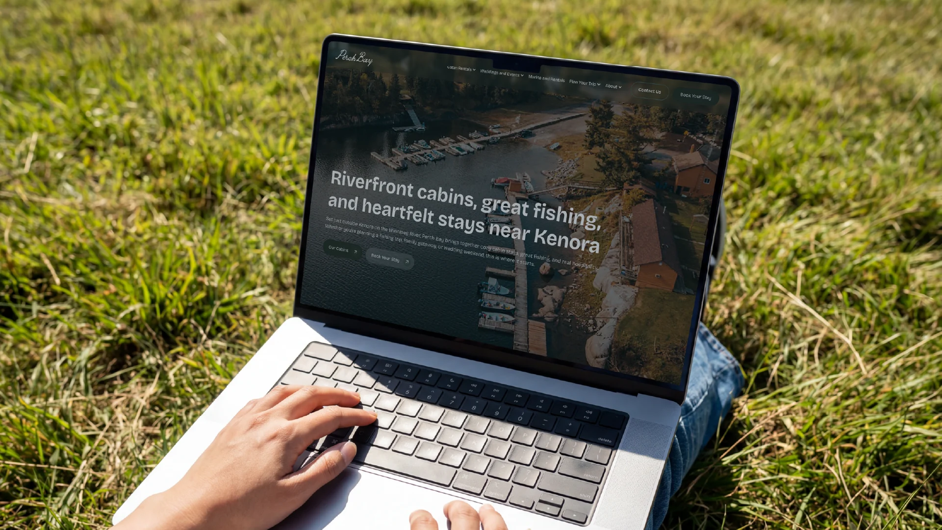 Perch Bay Resort website displayed on a laptop outdoors, featuring riverfront cabins, fishing and stays near Kenora.