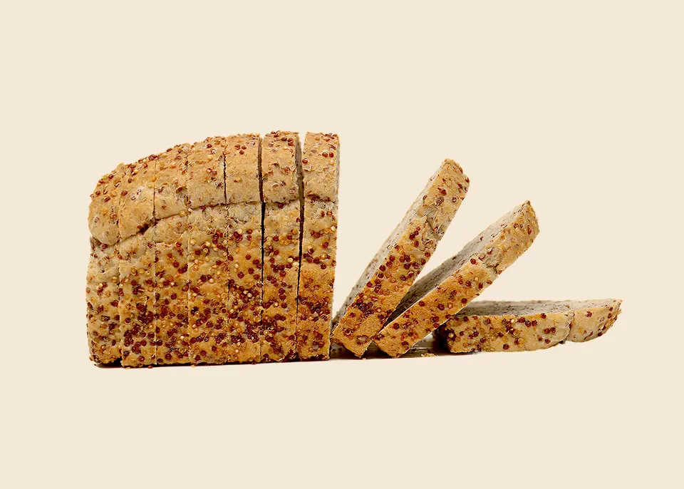 Loaf of multigrain bread partially sliced with some slices leaning on the side.