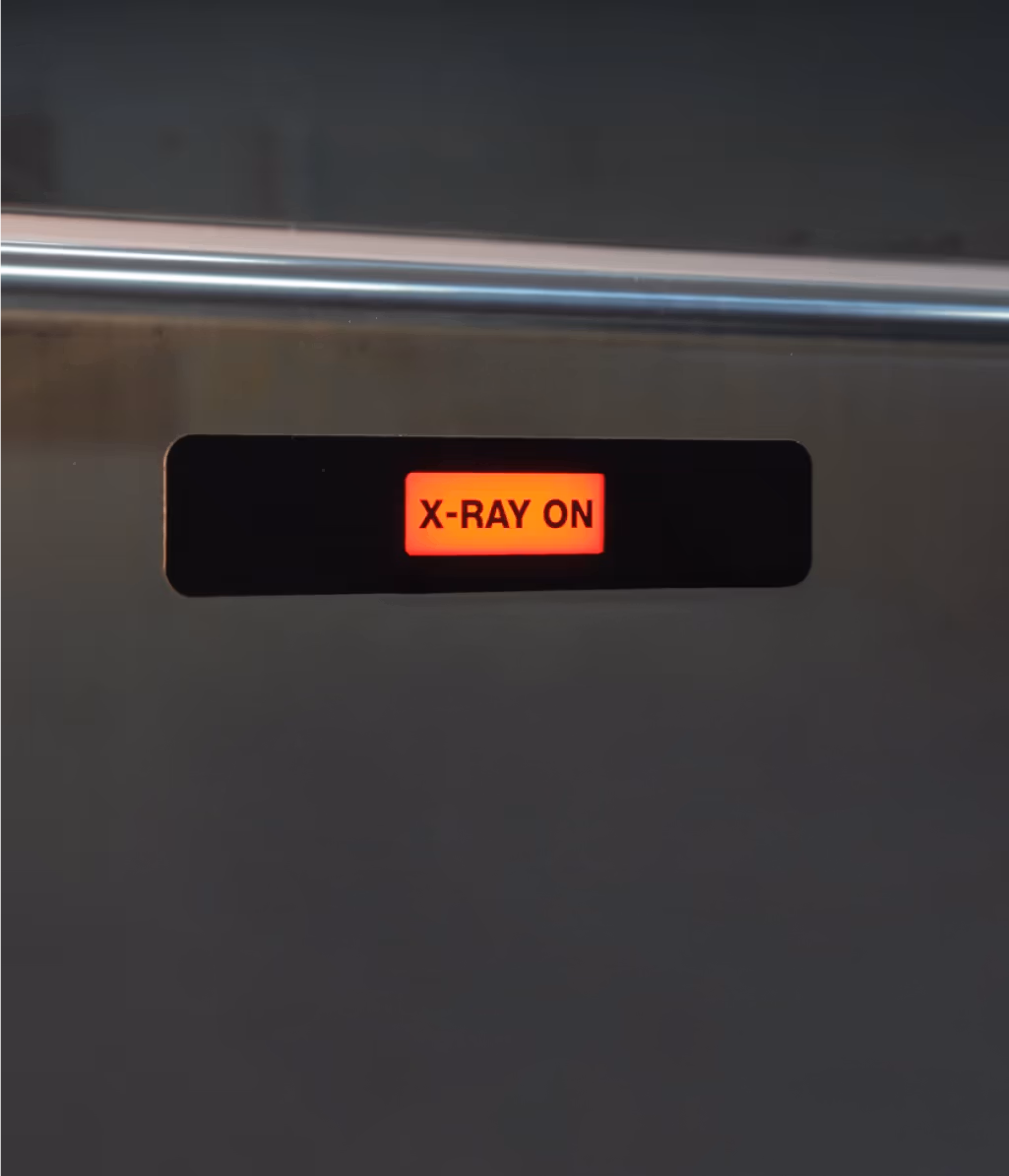 Red illuminated sign with black text reading 'X-RAY ON' on a dark background.