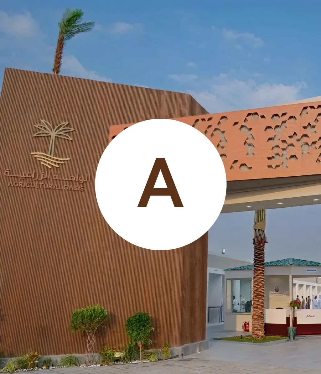 Exterior view of the Agricultural Oasis building with a corrugated brown facade, palm tree logo, and a modern entrance under a blue sky.
