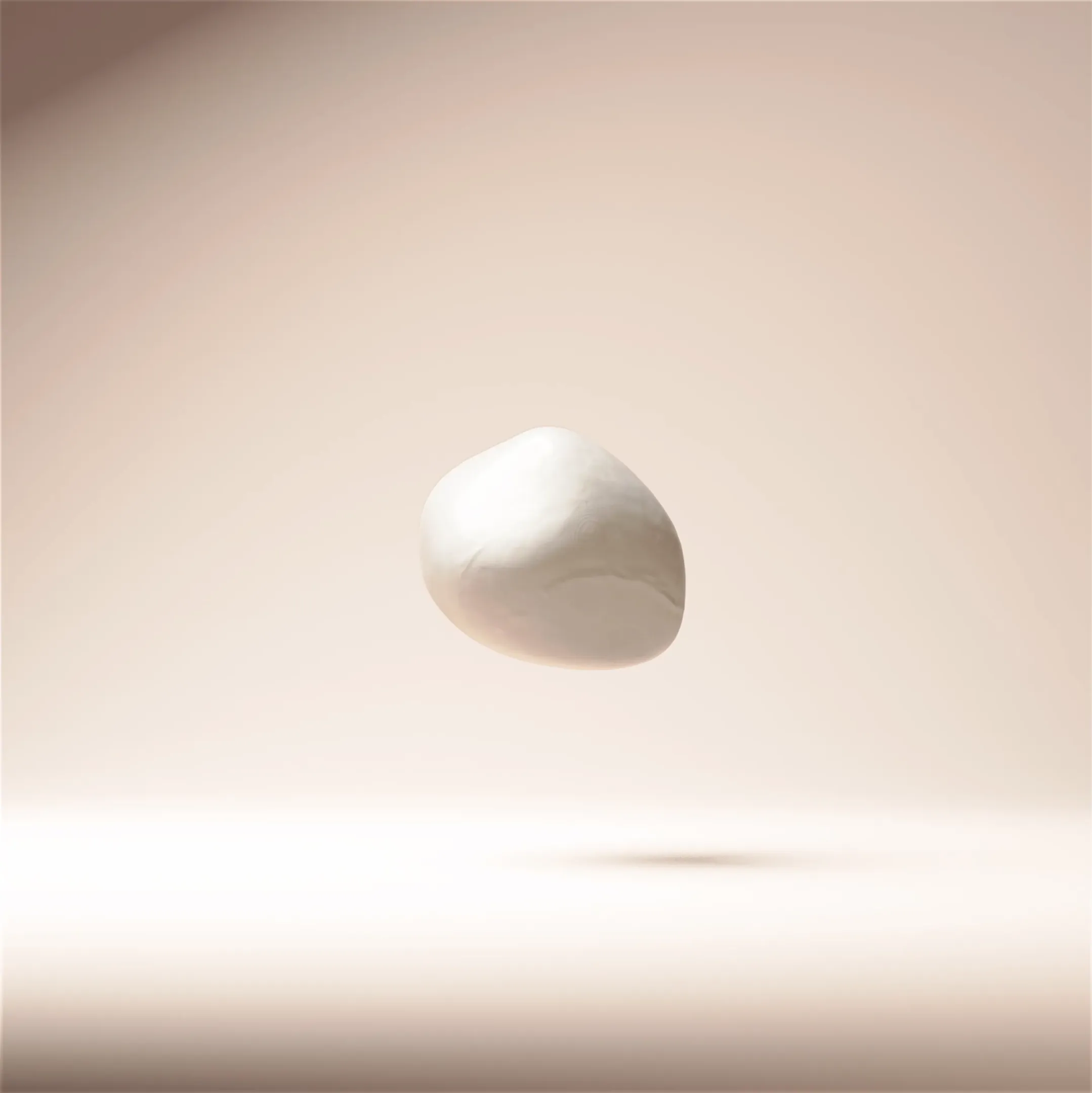 Smooth white pebble floating above a soft beige surface casting a shadow below.