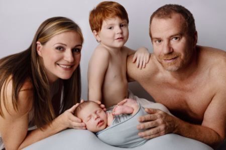 Ritratto di famiglia con neonato, genitori e fratellino — sessione fotografica neonato a Bologna, Imola, Ferrara di Claudia Spaziani.