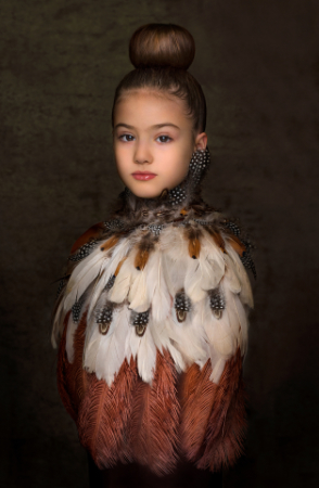 Ritratto artistico di ragazza con acconciatura raccolta e abito elaborato di piume – fotografia creativa di Claudia Spaziani, Bologna.