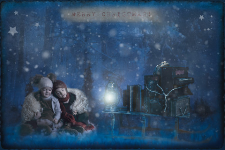 Bambini in abiti invernali in bosco innevato con lanterna in servizio fotografico natalizio fiabesco.