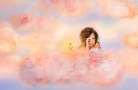 Bambino su nuvole pastello con telescopio in servizio fotografico fantasy ispirato a Peter Pan.