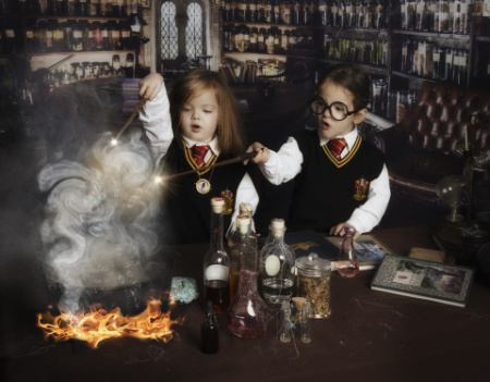 Bambini in uniforme di Hogwarts che preparano pozioni in servizio fotografico fantasy ispirato a Harry Potter.