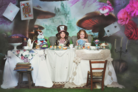 Bambini in costumi di Alice e Cappellaio Matto a tavola per servizio fotografico fiabesco ispirato ad Alice nel Paese delle Meraviglie.