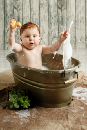Bambino in tinozza con paperella gialla in servizio fotografico smash cake primo compleanno.
