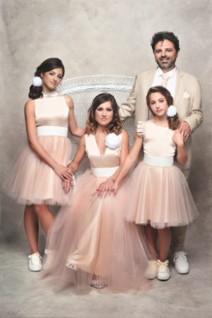 Foto di famiglia coordinata in rosa e beige a Bologna – Claudia Spaziani – Uomo in abito chiaro e tre donne in abiti rosa, accessori bianchi, posa formale in studio fotografico.