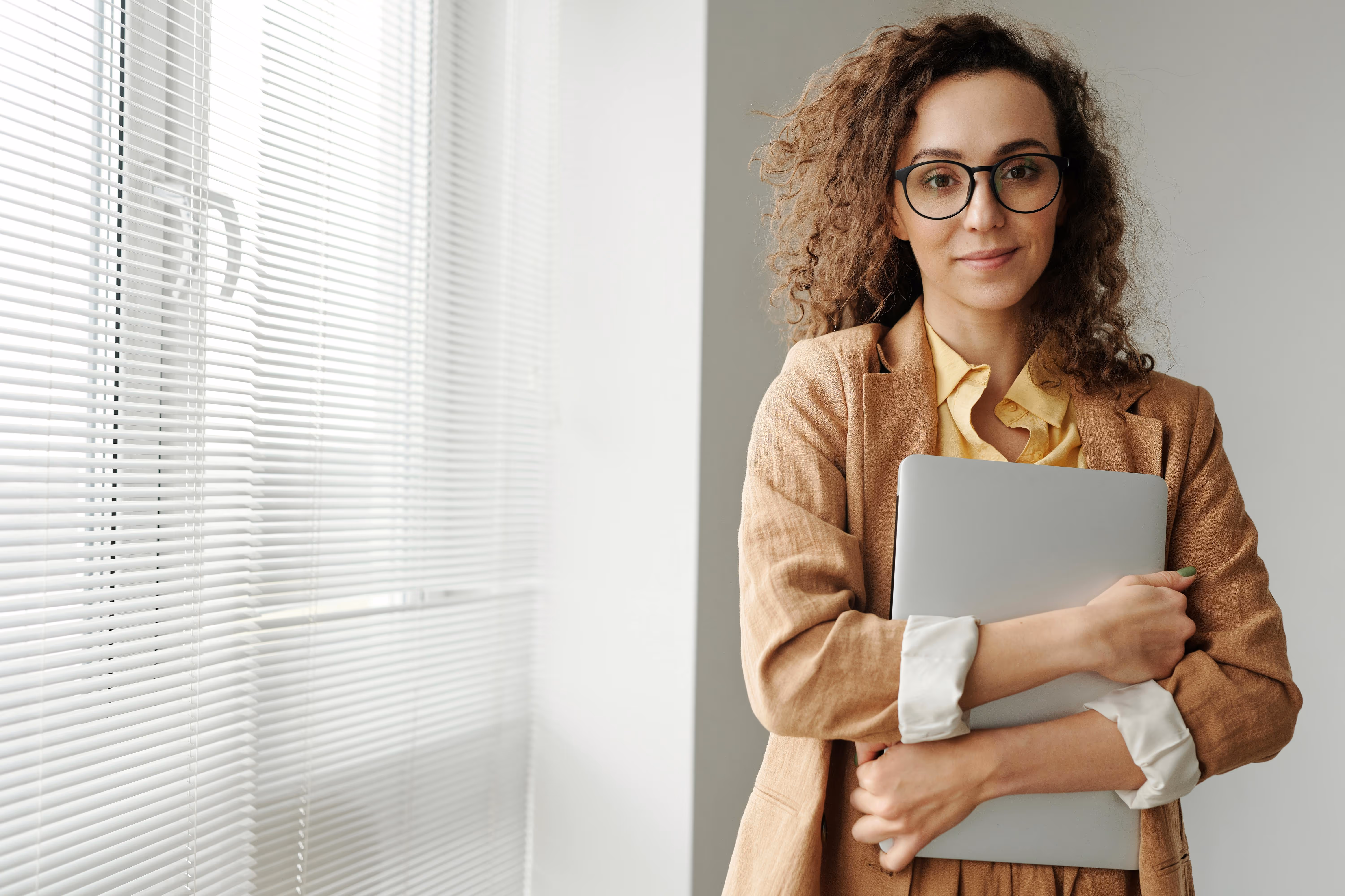 A picture of a woman in glasses holding a laptop