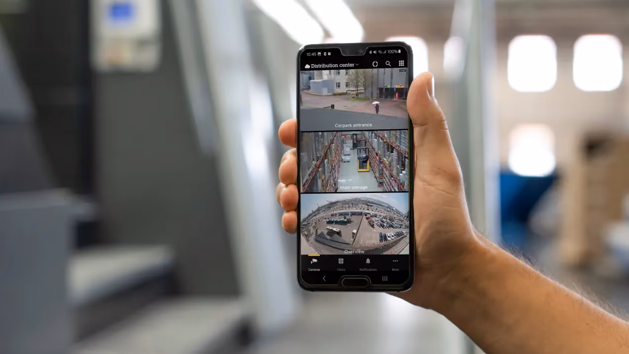 Someone holding up a mobile phone showing three different CCTV live streams