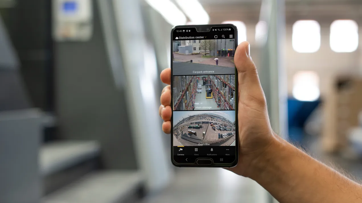 Someone holding up a mobile phone showing three different CCTV live streams