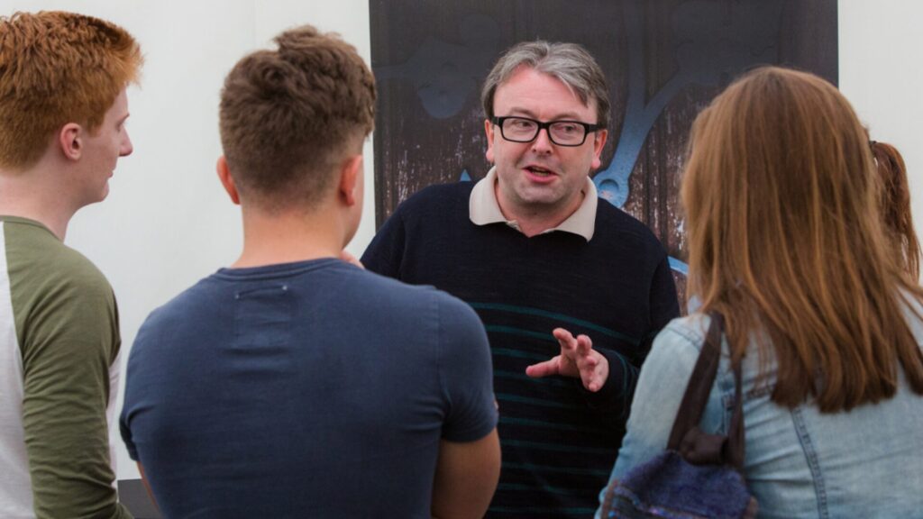 An instructor explaining something to three students standing in front of him