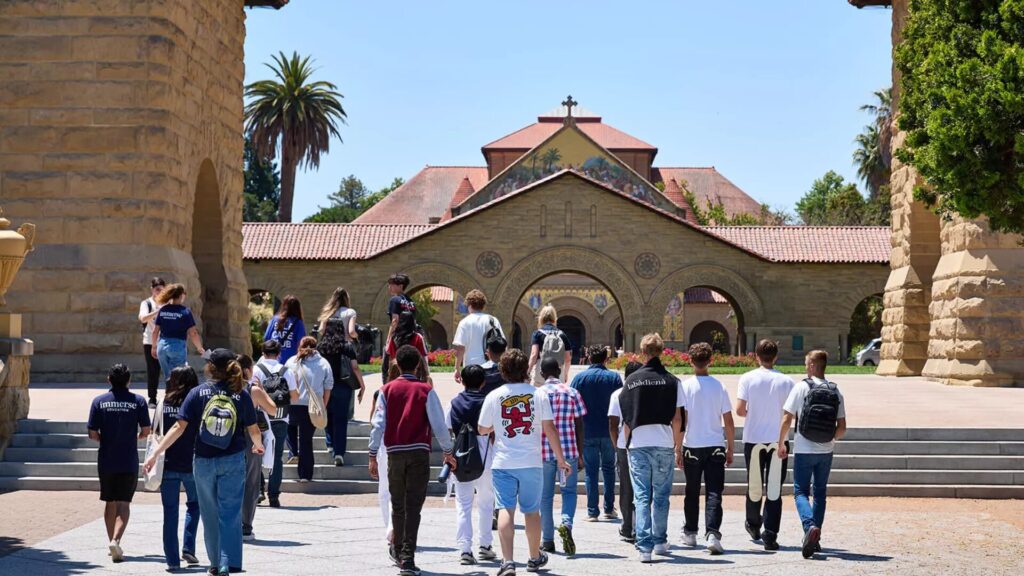 A group of students walking towards the steps of a church-like structure as part of a tour.