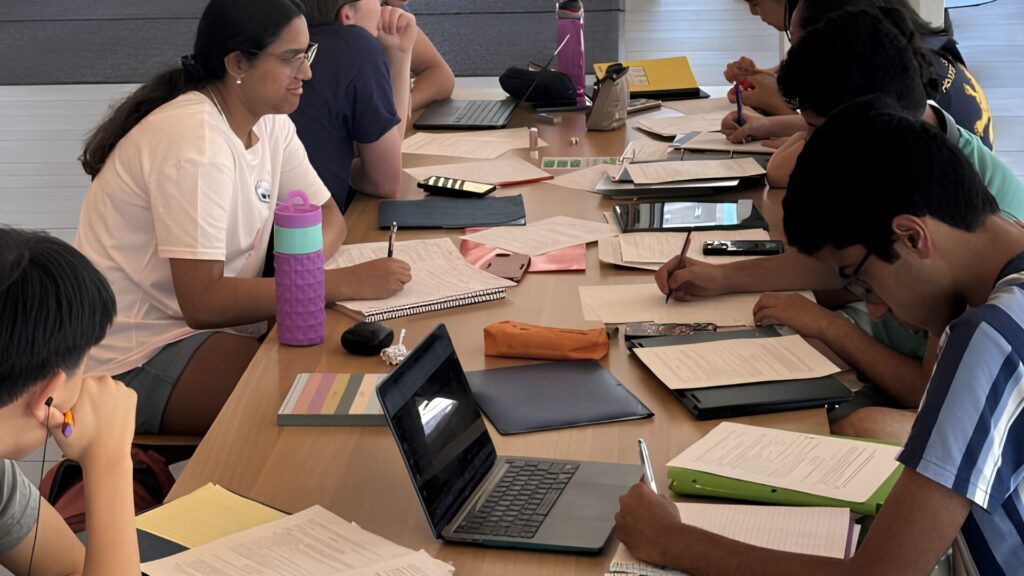 Students sitting together around a rectangular table and doing their individual work.