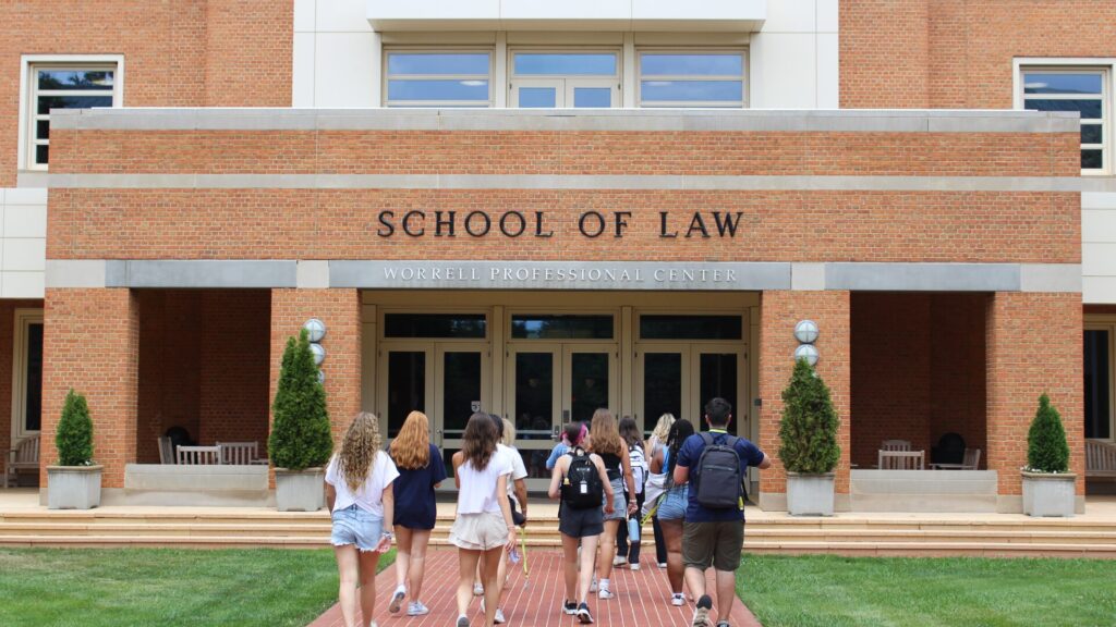 A group of students walking towards the 'school of law' building 