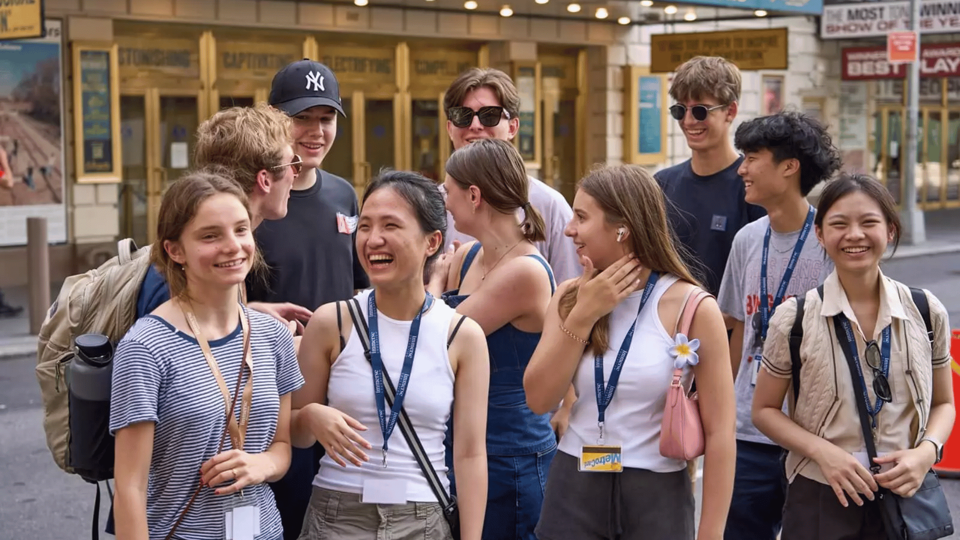 A collection of high-school students, gathered in a group, laughing and talking amongst themselves.
