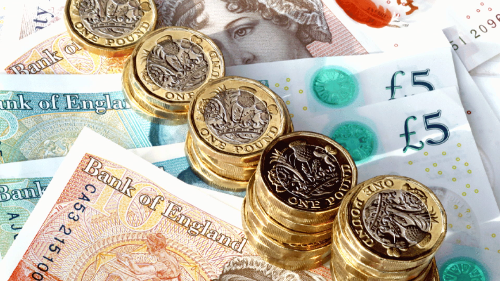Stacks of coins lying on top of 5 pound notes