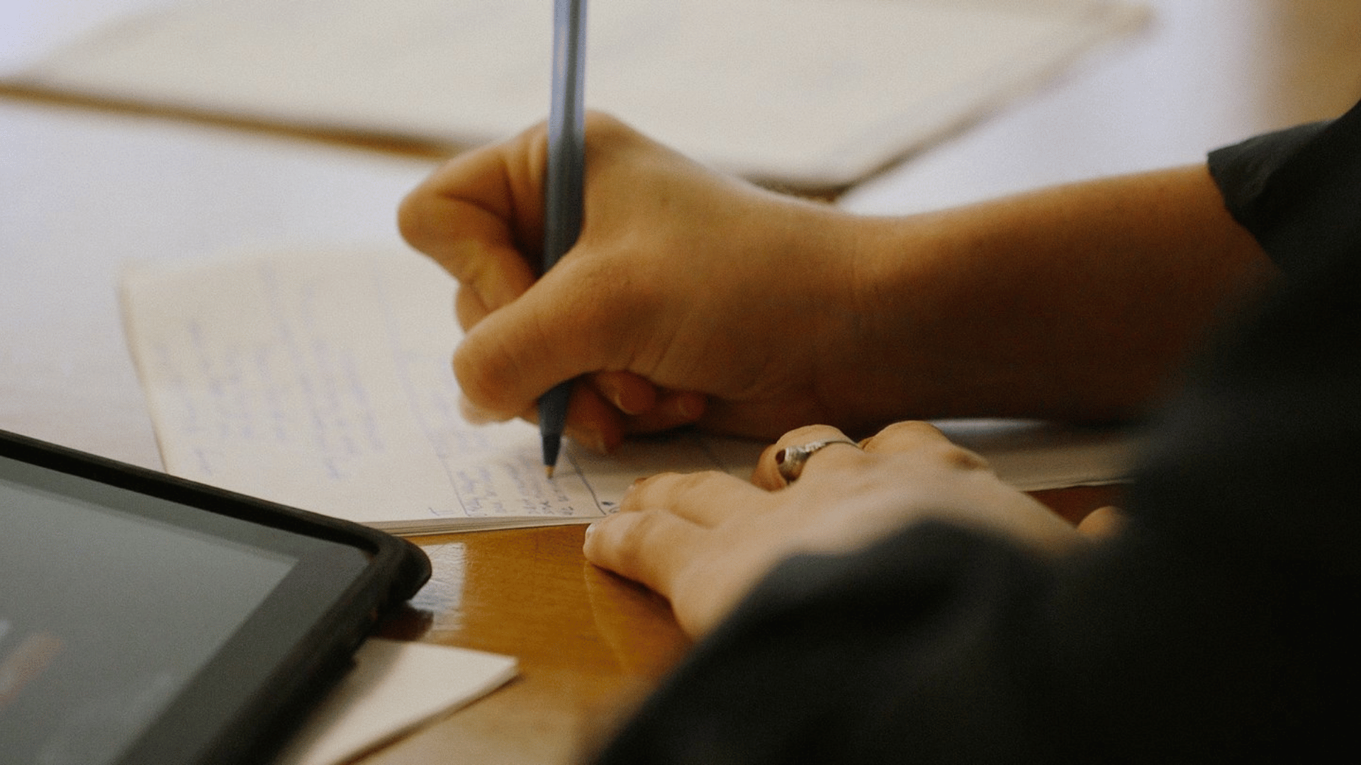 A student taking notes in a notebook using a pen