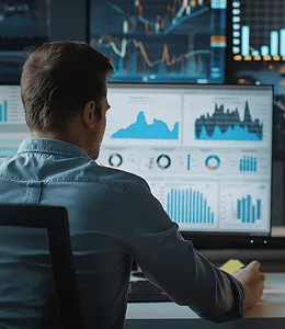 Man analyzing charts and graphs on multiple computer monitors.
