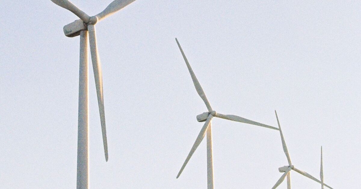 Several three-blade wind turbines against a pale sky 